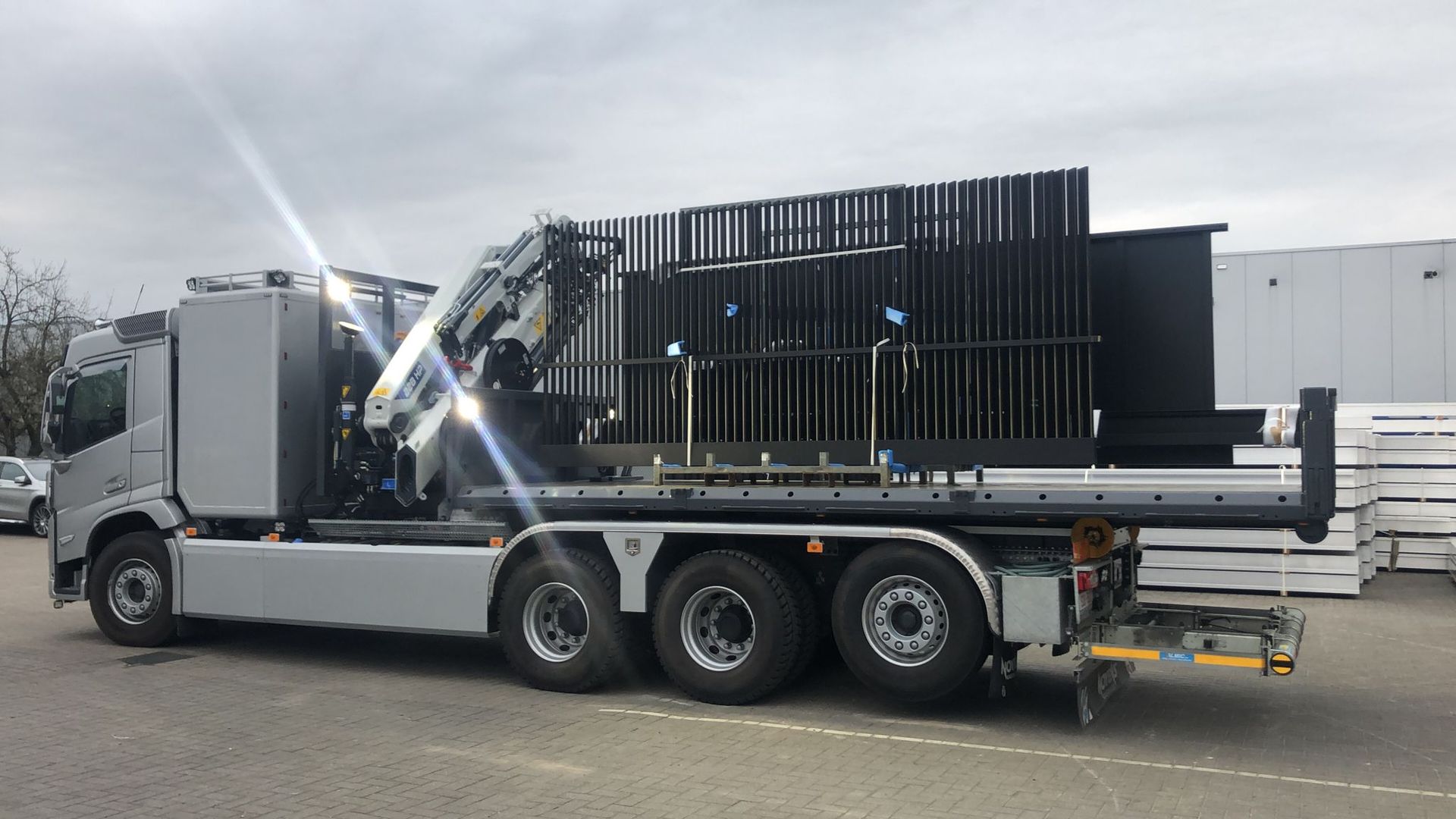 Metalen aanhangwagenplatform met gemonteerd transportrek voor glas of panelen, specialistische transportoplossing.